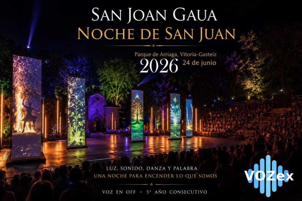 Espectáculo nocturno de San Joan Gaua en el Parque de Arriaga de Vitoria-Gasteiz, con la ermita al fondo, público en las gradas, tótems verticales con proyecciones de fuego y estaciones del año, iluminación escénica y los logos de la Diputación Foral de Álava y Vozex.