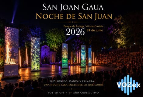 Espectáculo nocturno de San Joan Gaua en el Parque de Arriaga de Vitoria-Gasteiz, con la ermita al fondo, público en las gradas, tótems verticales con proyecciones de fuego y estaciones del año, iluminación escénica y los logos de la Diputación Foral de Álava y Vozex.